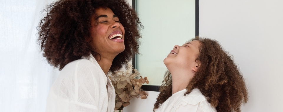 une-femme-et-sa-fille-avec-des-cheveux-frisés-qui-rient-aux-éclats